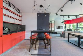 Salle de pause avec cuisine équipée, table haute et tabourets rouges