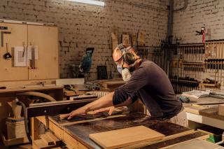 Menuisier masqué qui travaille un panneau de bois dans son atelier