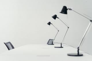 Trois lampes de bureau articulées noires sur un plan de travail blanc