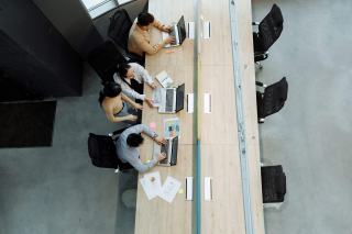 Vue plongeante sur une longue table de travail partagée en bois avec ordinateurs portables