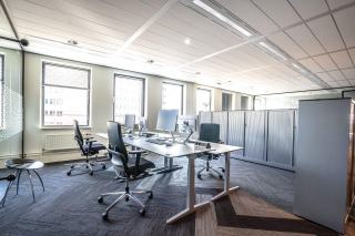 Open space lumineux aux postes de travail regroupés sous de grandes fenêtres