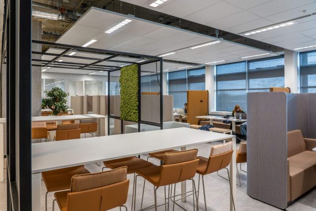 Concevoir des bureaux professionnels adaptés au travail réel Espace de travail collaboratif avec grande table, mur végétal et cabines vitrées