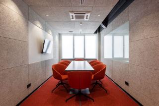 Salle de réunion aux murs habillés de panneaux acoustiques en feutre et sièges rouges