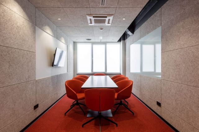 Panneaux et cloisons acoustiques pour absorber le bruit des bureaux Salle de réunion aux murs habillés de panneaux acoustiques en feutre et sièges rouges