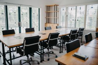 Grande table de réunion en bois entourée de sièges noirs dans une salle vitrée