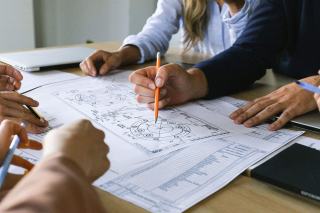 Mains qui annotent des plans et des croquis lors d'une réunion de projet