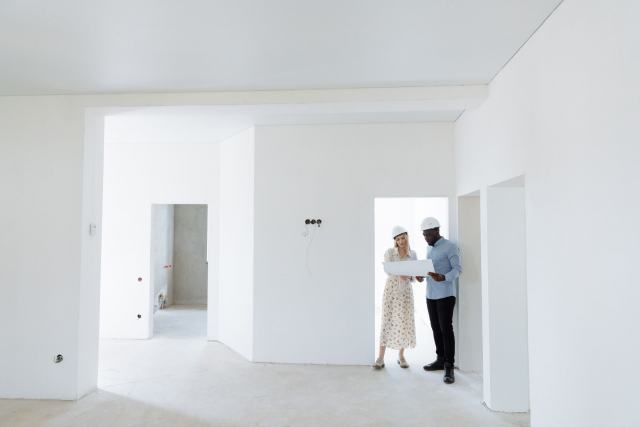 Du diagnostic à l'emménagement, conduire l'agencement d'un bureau Deux personnes en casque de chantier dans un local de bureaux vide en cours d'aménagement