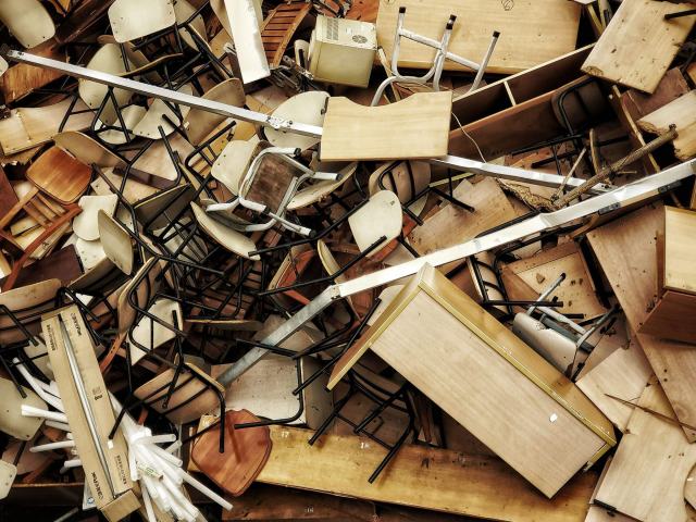 Que faire du mobilier de bureau usagé : réemploi, don et recyclage Amas de chaises et de tables en bois démontées en attente de recyclage
